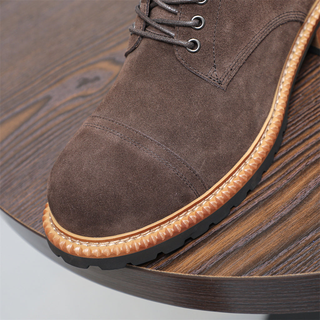 Close-up of men's dark brown suede chukka boot toe and lace eyelets with tan trim