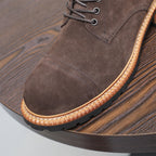 Close-up of men's dark brown suede chukka boot toe and lace eyelets with tan trim