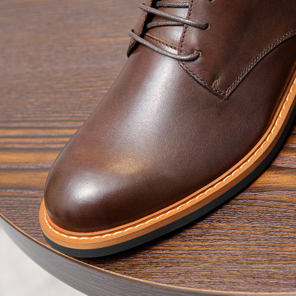Dark brown leather ankle boot toe with orange welt and stitched panel details