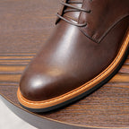 Dark brown leather ankle boot toe with orange welt and stitched panel details