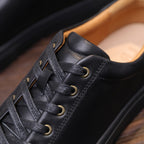 Black leather sneaker upper detail with gray laces and perforated eyelets.