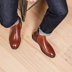 Men's brown leather side-zip dress boots worn with dark jeans