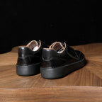 Black leather lace-up sneakers, rear view, padded collar, contrast stitching.