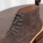 Close-up of men's dark brown suede lace-up chukka boot with metal eyelets and heel tab