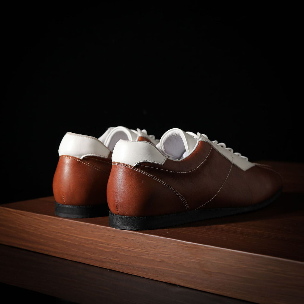 Men’s leather sneakers, brown and white lace-up shoes, heel-to-sole view on stand