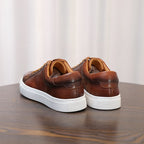 Men's brown leather sneakers, rear view with white rubber sole and cushioned collar