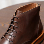 Dark brown leather lace-up ankle boot with stitched upper and orange trim