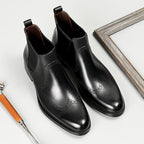 Black leather chelsea dress boots with brogue-style side perforations and elastic gore