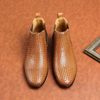 Pair of brown woven leather chelsea boots with elastic side panels and padded collar