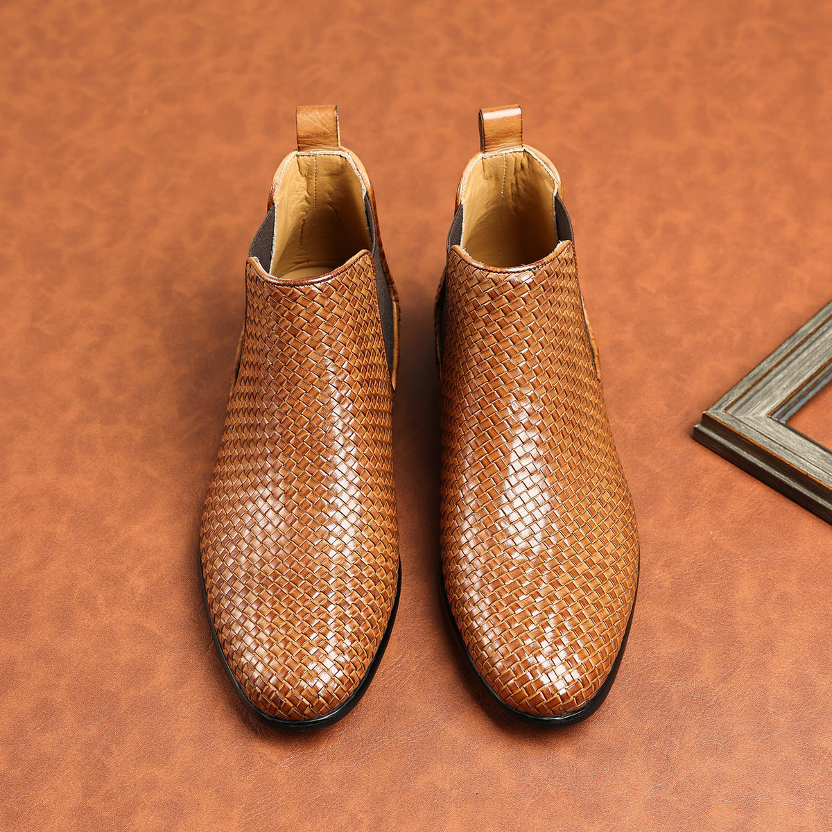 Pair of brown woven leather chelsea boots with elastic side panels and padded collar