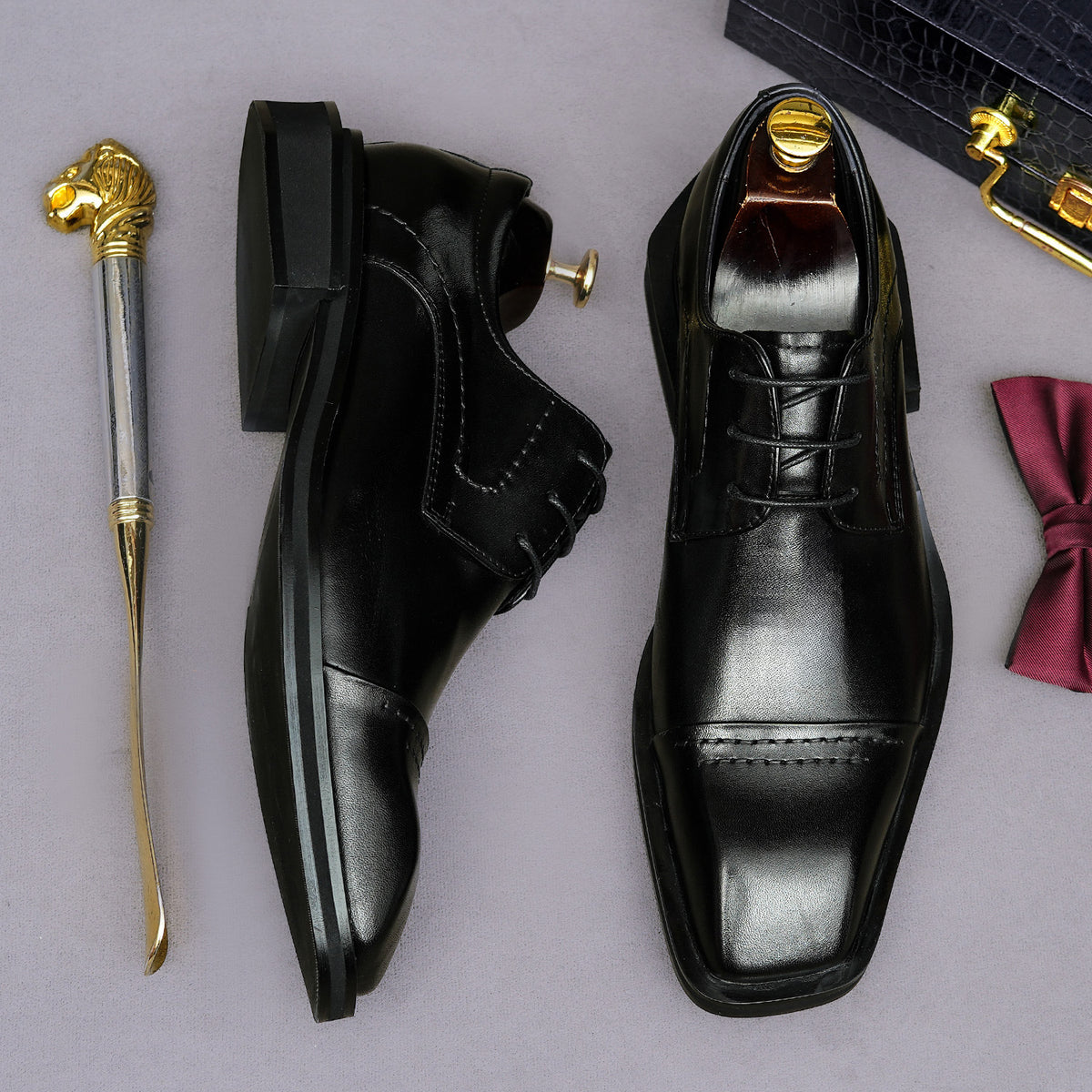 Men's black leather lace-up derby dress shoes, pointed toe with stitched sole edge detail.