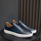 Men's leather sneakers in blue with black laces, white sole, and tan lining.
