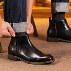 Black leather pointed-toe side-zip dress boot with tan trim; worn with dark pants