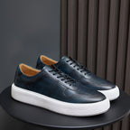 Leather sneakers, dark blue-green, lace-up front with white rubber sole.