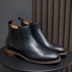 Pair of dark blue Chelsea dress boots on display with side elastic and tan edge stitching