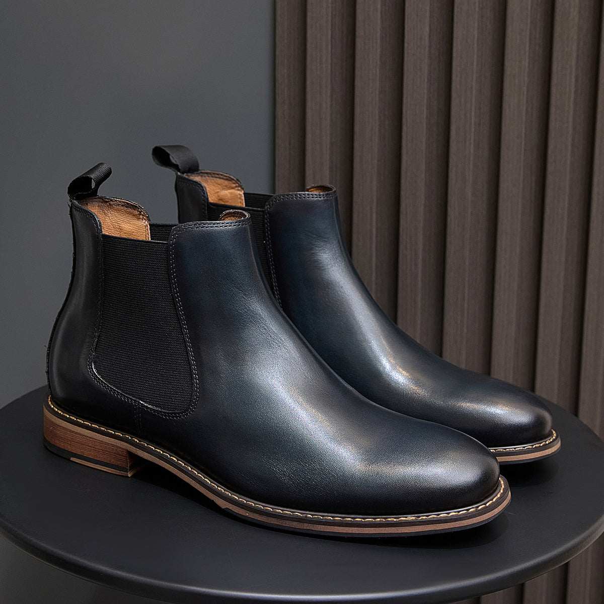 Pair of dark blue Chelsea dress boots on display with side elastic and tan edge stitching