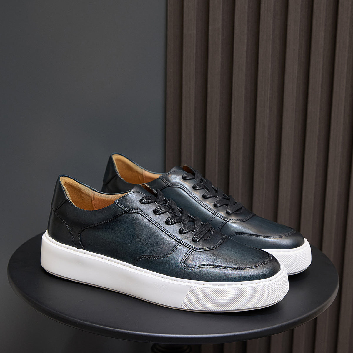 Men's dark leather low-top sneakers with black laces and textured white platform sole