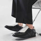 Black and white leather lace-up sneakers with clean minimalist side stitching.