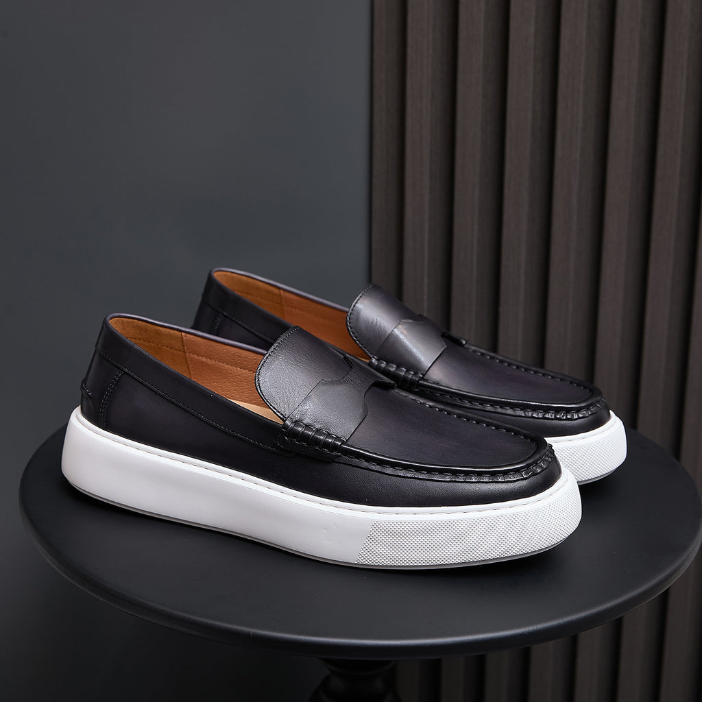 Pair of black leather slip-on sneakers with moccasin stitching and white platform sole