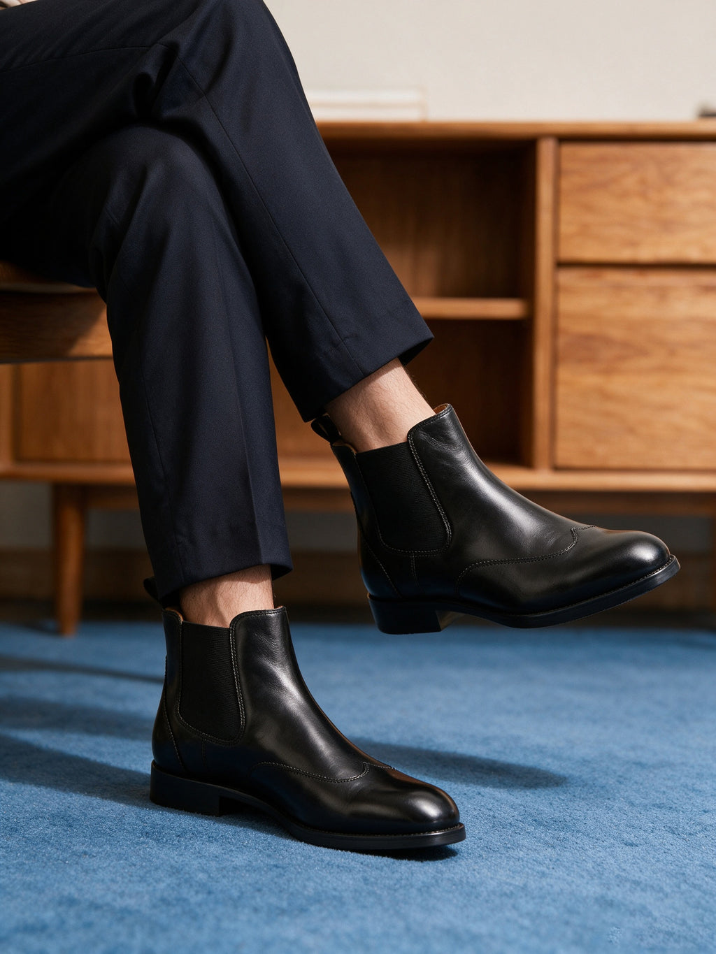 Black pointed-toe chelsea boots with elastic side panels, worn with rolled pant cuffs