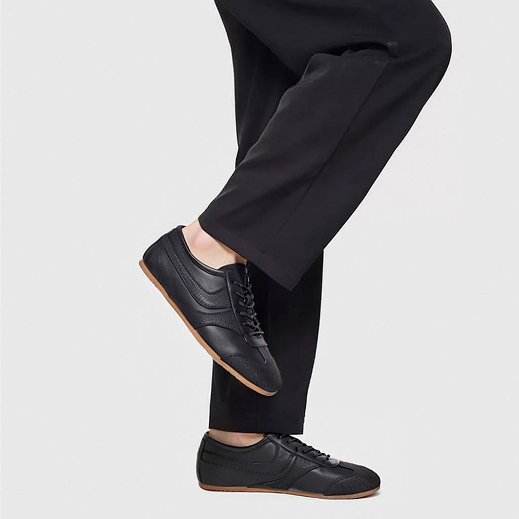 Men's black leather sneakers on feet; lace-up front and gum-style sole