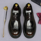 Pair of men's pointed-toe leather derby shoes, lace-up with brogue perforations and dark patina.