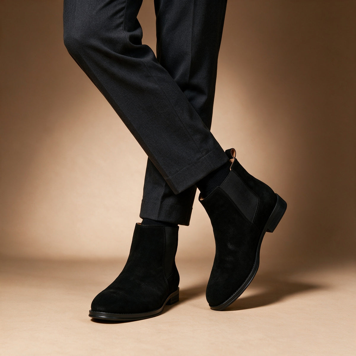 Black suede pointed-toe Chelsea dress boots worn with dark trousers