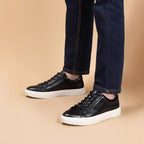 Men's black leather lace-up sneakers on feet with low-profile white sole