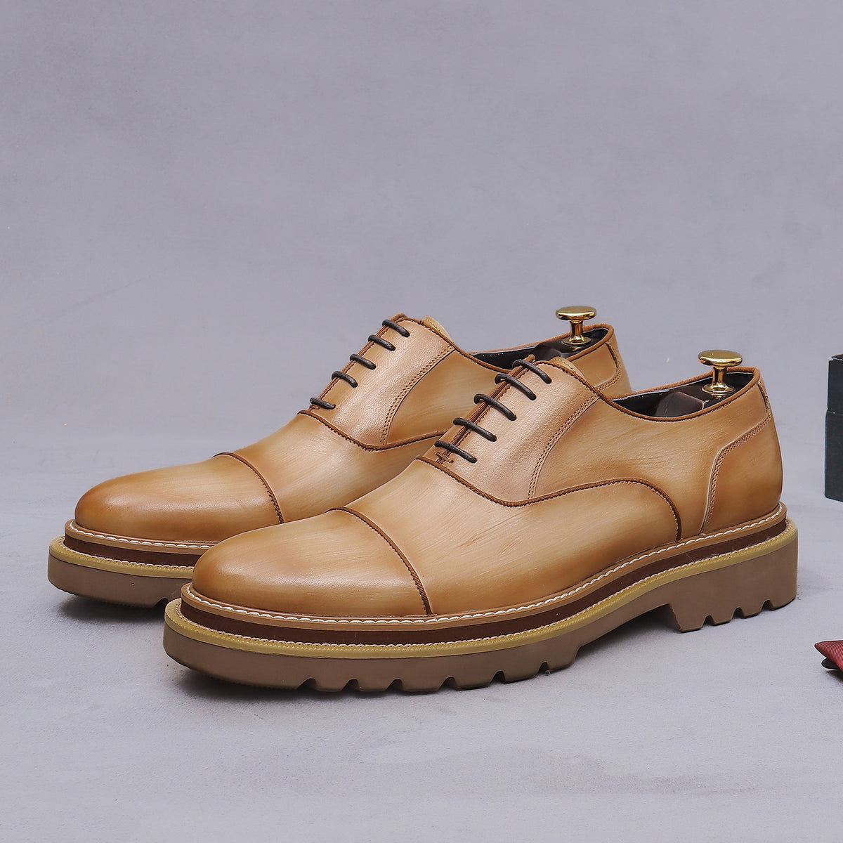 Tan lace-up oxford shoes with brogue stitching and chunky lug sole platform.