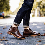 Dark brown leather lace-up chukka boots on street, plain toe and treaded outsole.