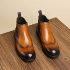 Men's brown leather chelsea dress boots, side view with elastic gore and textured brogue toe.