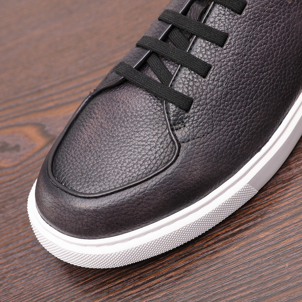 Black genuine leather sneaker with lace-up straps and rounded toe, white rubber sole.