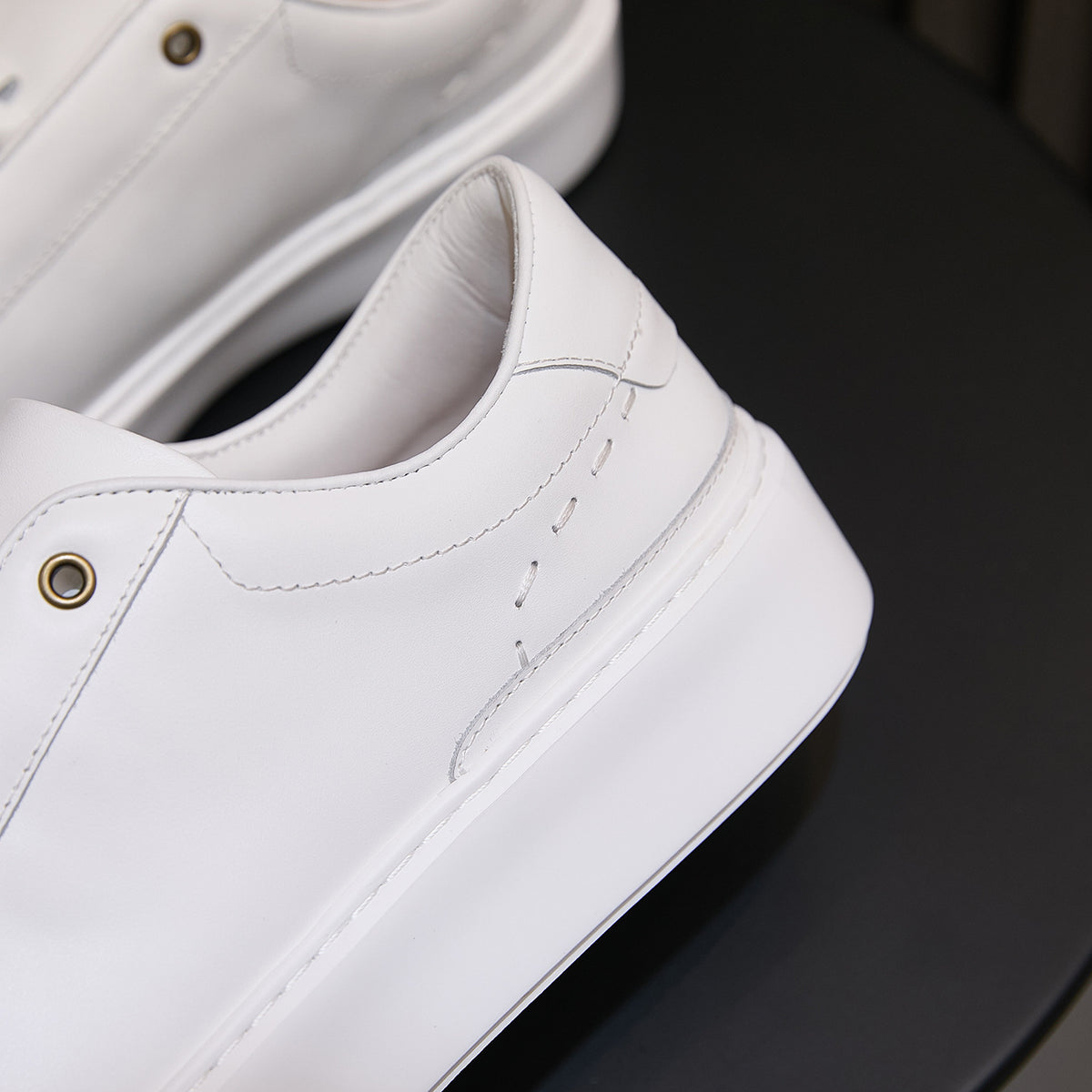 White leather sneaker upper close-up with stitching, eyelets, and lace channel