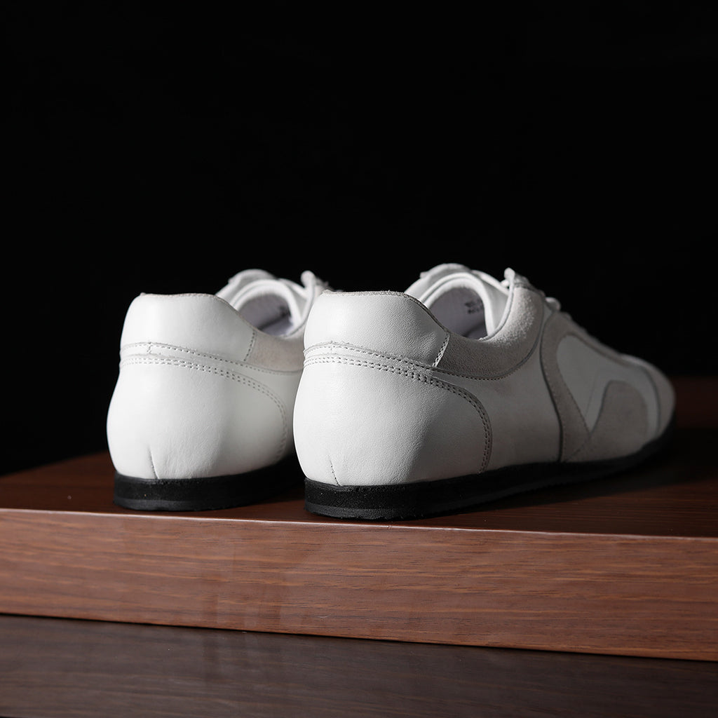 White leather sneakers from the heel, showing back seam and padded collar.