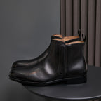 Black leather ankle boots with pointed cap toe and side zip, side view