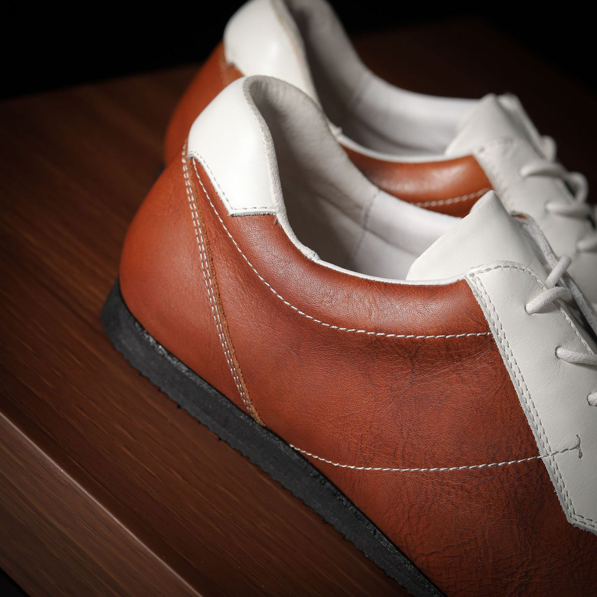 Close-up of men’s leather sneaker side, brown upper with white trim and lace area