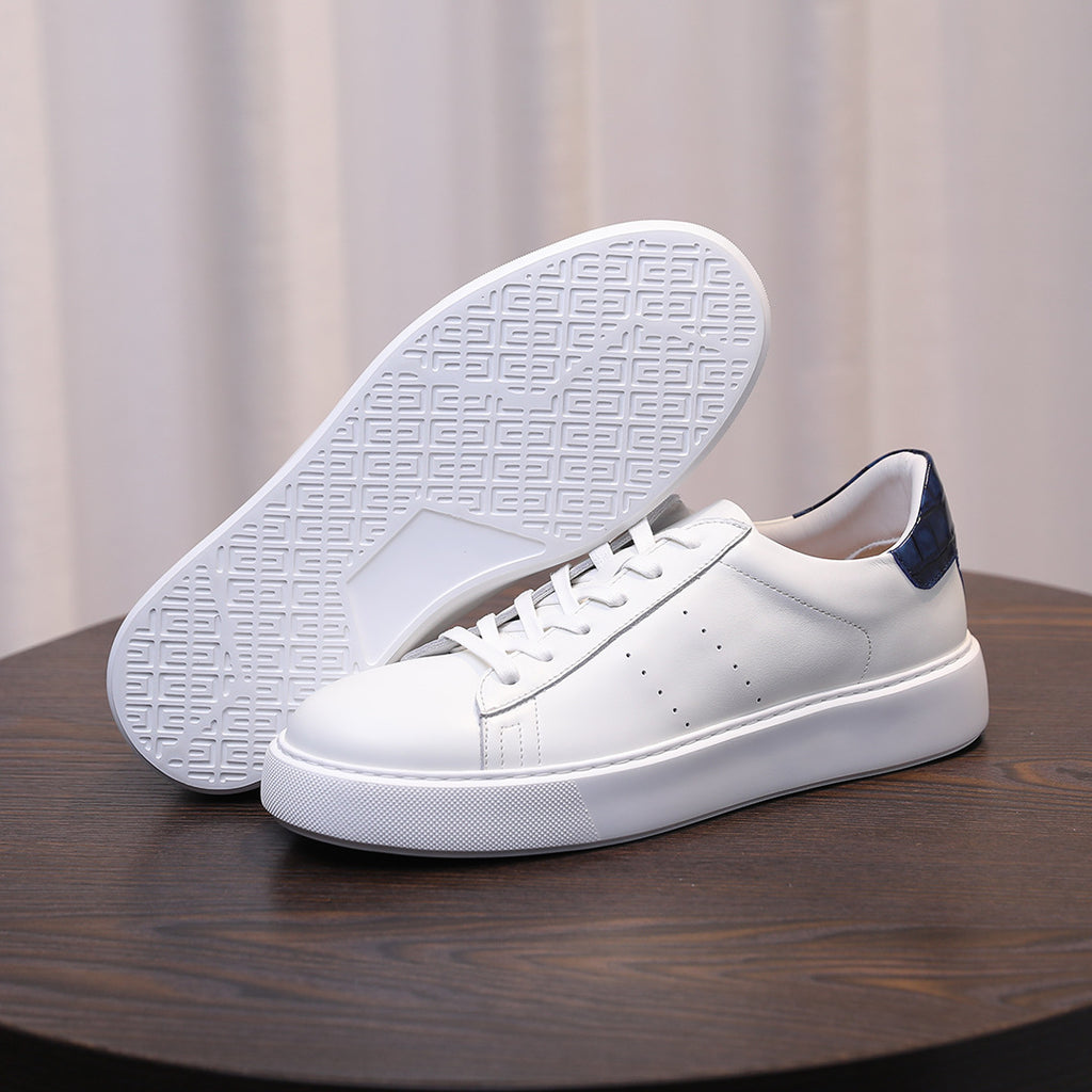 White leather sneakers with textured rubber outsole and dark blue heel lining accents.