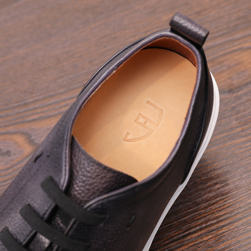 Black genuine leather sneaker showing tan insole and lace-up vamp detail.