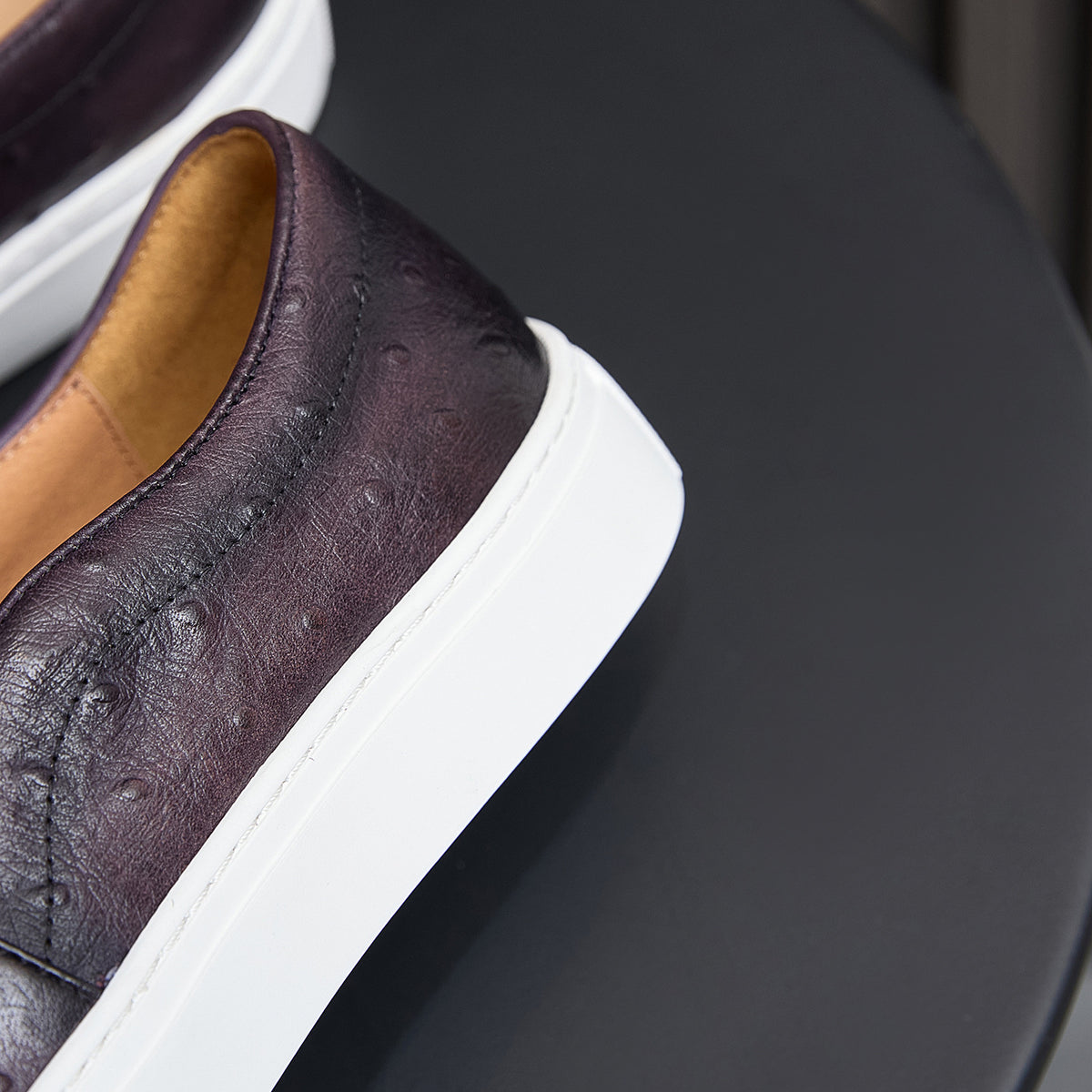 Dark leather sneaker with white sole edge and tan inner lining detail