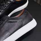 Black leather sneaker side with smooth stitching, cushioned collar, and white sole