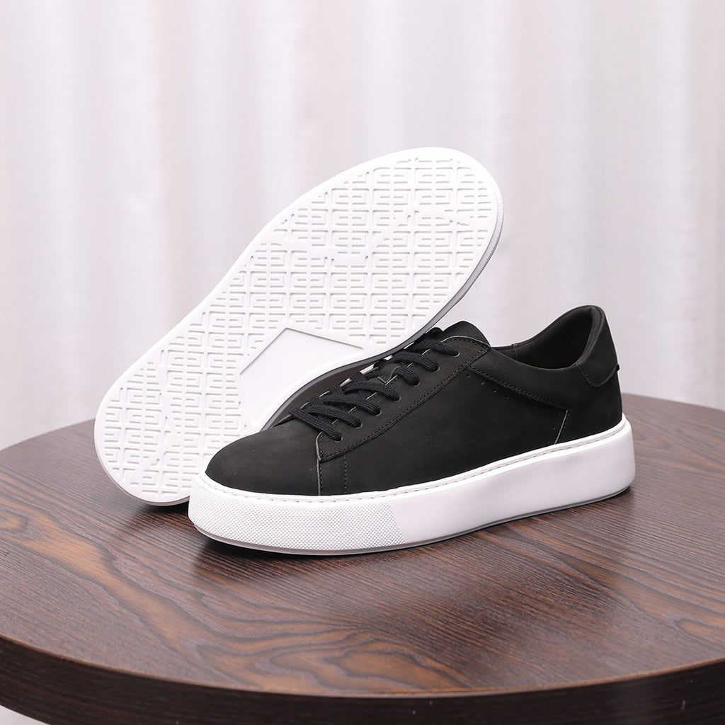 Black leather sneakers shown from underneath with textured white outsole