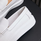 White leather slip-on sneakers with stitched side panels and padded collar