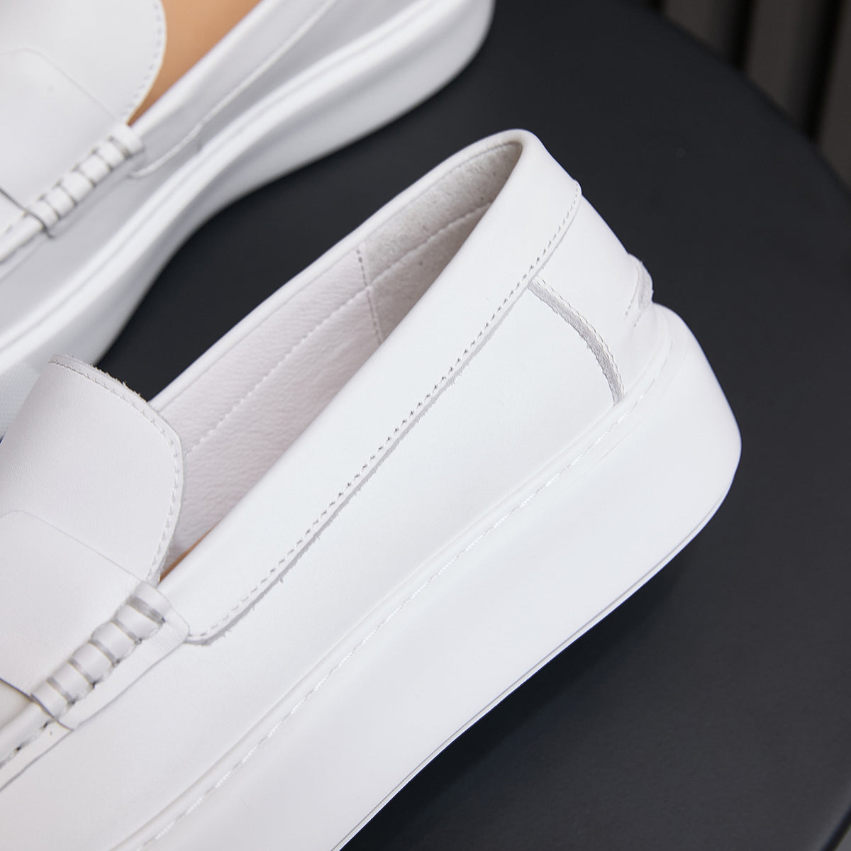 White leather slip-on sneakers with stitched side panels and padded collar