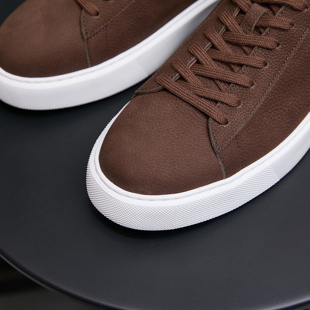Men's brown leather sneakers close-up, laced upper with textured leather panels