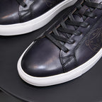 Black leather lace-up sneaker close-up with detailed stitching and white rubber sole
