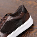 Brown leather sneakers close-up at side, lace-up with white rubber sole