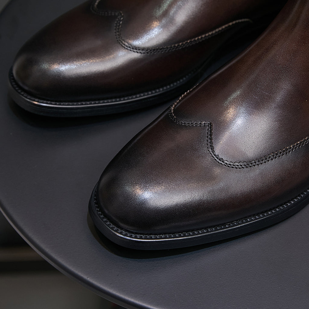 Pointed-toe chelsea boot toe and side seam details, dark brown finish