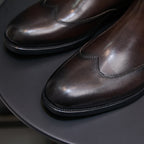 Pointed-toe chelsea boot toe and side seam details, dark brown finish
