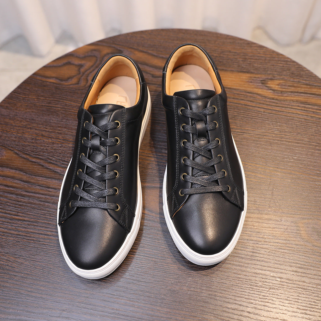 Black leather sneakers with white rubber toe caps and tan inner lining.