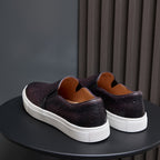 Pair of dark leather sneakers with white rubber soles and cushioned heel collars